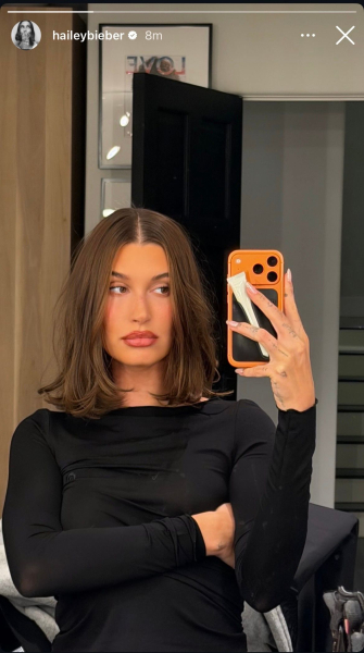 Hailey Bieber poses in the mirror with a shorter hairstyle. Her hair is now just above shoulder length.